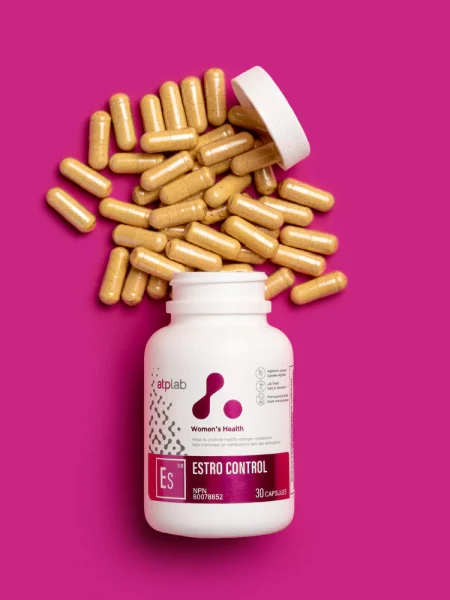 ATP Lab Estro Control Nahrungsergänzungsmittel mit geöffnetem Flaschendeckel und verschütteten Kapseln auf pinkem Hintergrund