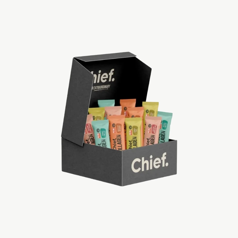 Eine offene, schwarze Verpackungsbox der Marke Chief., gefüllt mit Kollagen-Proteinriegeln, die für ihre reinen Inhaltsstoffe ohne unnötige Zusatzstoffe bekannt sind. Die bunten Einzelverpackungen der Riegel (u.a. Erdnussbutter, Haselnuss Brownie) sind sichtbar
