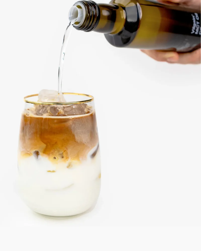 Vilgain MCT Öl C8 wird in einen geschichteten Eiskaffee gegossen für einen Bulletproof Coffee Effekt.